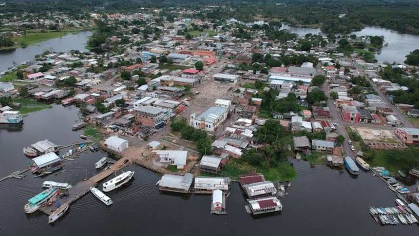 Vista aérea de uma cidade ribeirinha na Amazônia, com casas, barcos e rio. Manaquirii