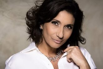 Zizi Possi sorrindo, usando colar e camisa branca