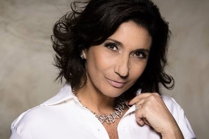 Zizi Possi sorrindo, usando colar e camisa branca
