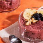 Açaí com banana e castanhas em tigela de vidro.