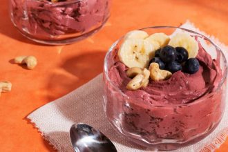 Açaí com banana e castanhas em tigela de vidro.