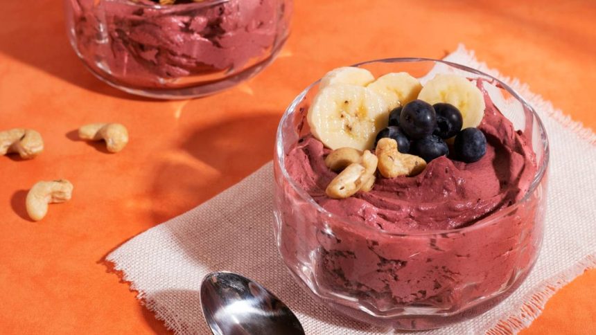 Açaí com banana e castanhas em tigela de vidro.