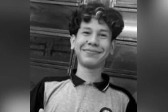 Adolescente sorrindo, em preto e branco.