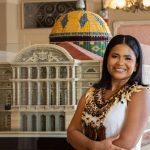 Advogada amazonense sorrindo ao lado de réplica de prédio