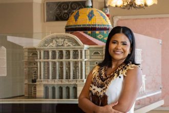 Advogada amazonense sorrindo ao lado de réplica de prédio