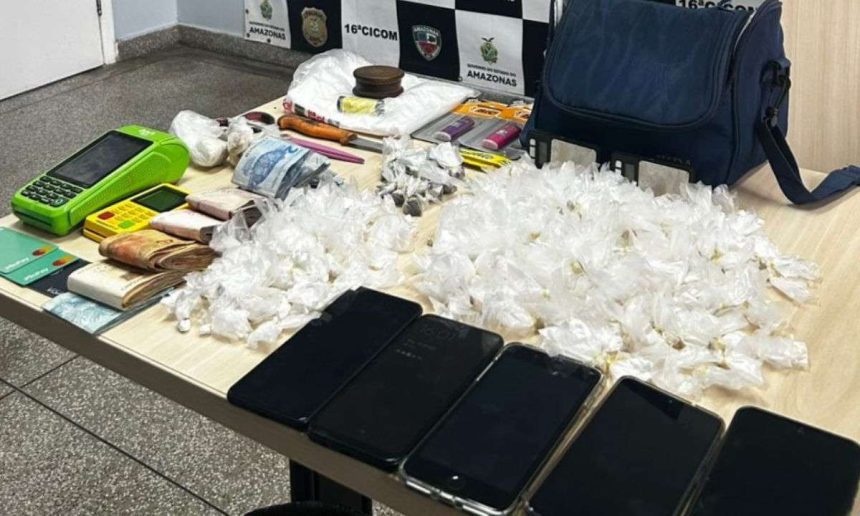 Apreensão de drogas e objetos em uma mesa, incluindo celulares, dinheiro e embalagens de entorpecentes.