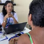 Assistente orienta cidadã em mutirão de serviços, com foco em tarifa social da água.