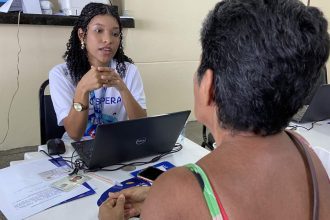 Assistente orienta cidadã em mutirão de serviços, com foco em tarifa social da água.
