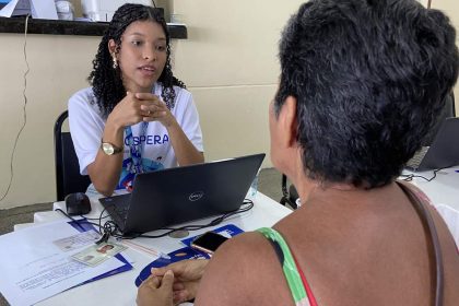 Assistente orienta cidadã em mutirão de serviços, com foco em tarifa social da água.