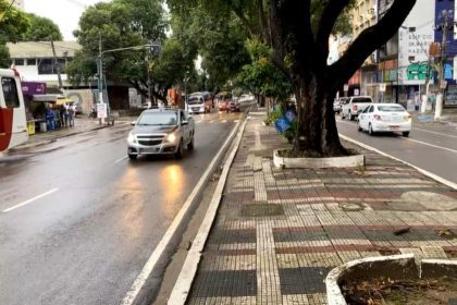 Avenida Getúlio Vargas com carros e ônibus em via molhada.