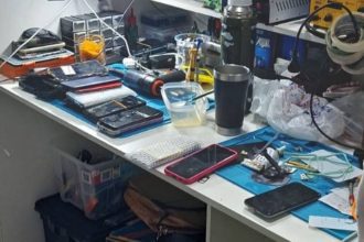 Bancada de trabalho com celulares, ferramentas e equipamentos eletrônicos.