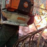 Bombeiro florestal usando soprador para conter incêndio florestal.