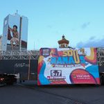 Caminhão com banner '#Sou Manaus Passo a Paço 2025' em frente a prédio com grafite.