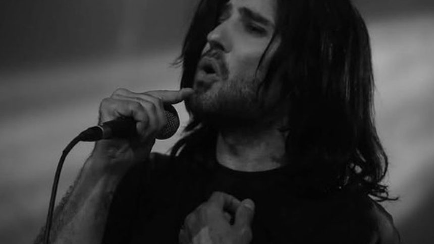 Cantor com cabelo longo cantando no microfone