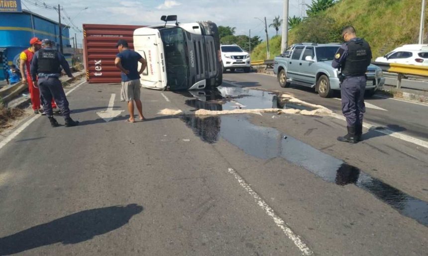 Carreta com contêiner tombada na avenida Governador José Lindoso, com policiais no local.