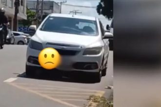 Carro branco estacionado na rua com emoji triste. Cena em Paraíso, Rua Presidente Floriano Peixoto.