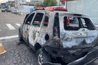 Carro destruÃdo por incêndio em rua de Manaus, mostrando danos extensos.