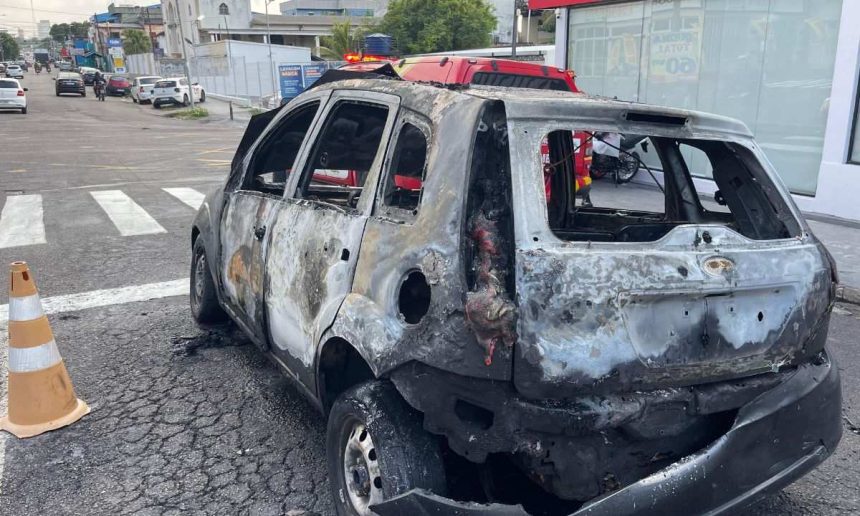 Carro destruído por incêndio em rua de Manaus, mostrando danos extensos.