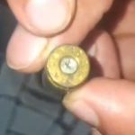 Cartucho de bala dourado sendo segurado por uma mão