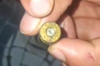 Cartucho de bala dourado sendo segurado por uma mão