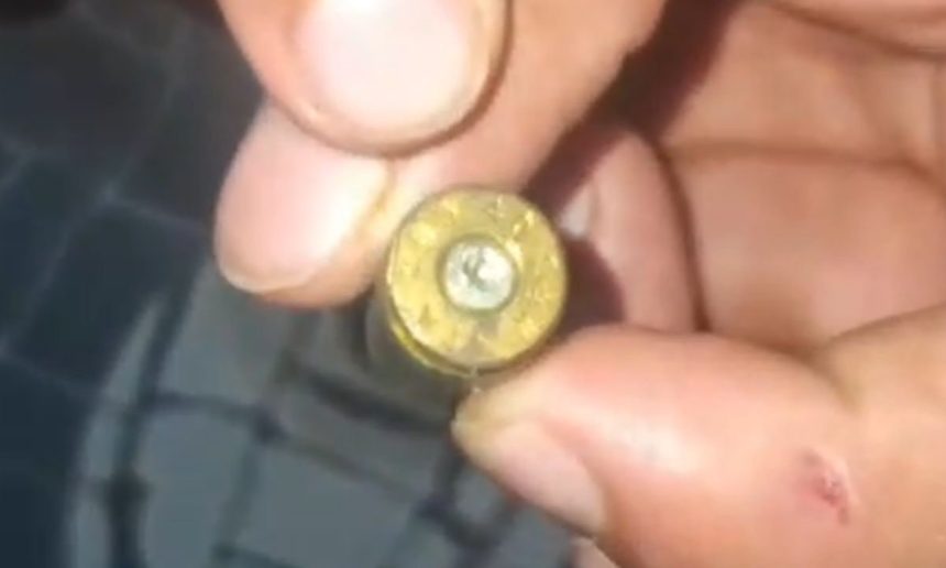 Cartucho de bala dourado sendo segurado por uma mão