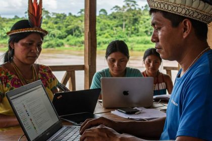 Comunidade indígena em reunião, utilizando laptops e acessando informações