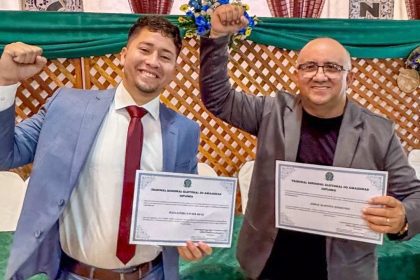 Dois homens sorrindo com diplomas em mãos, comemorando a conquista. Prefeito e vice-prefeito de Caapiranga cassados.