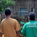 Dois indivíduos observando uma construção de madeira, possivelmente em contexto de vigilância em saúde.