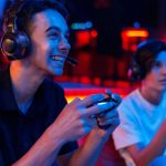 Dois jovens gamers jogando videogame com fones de ouvido e controles