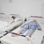 Dois manequins em camas de hospital, simulando pacientes.