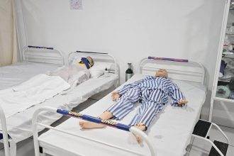 Dois manequins em camas de hospital, simulando pacientes.