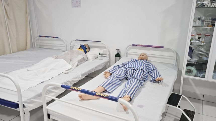 Dois manequins em camas de hospital, simulando pacientes.