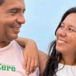 Duas pessoas sorrindo, com um homem usando uma camiseta com a palavra 'Banzerê'.