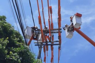 Eletricistas em trabalho de manutenção na rede elétrica, utilizando plataformas elevatórias, em Manaus.