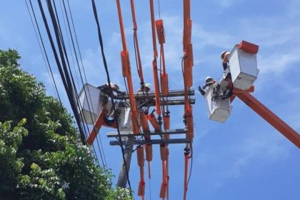 Eletricistas em trabalho de manutenção na rede elétrica, utilizando plataformas elevatórias, em Manaus.
