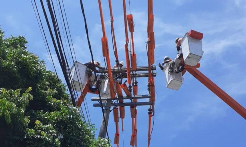 Eletricistas em trabalho de manutenção na rede elétrica, utilizando plataformas elevatórias, em Manaus.