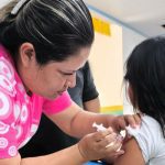 Enfermeira aplicando vacina HPV em criança.