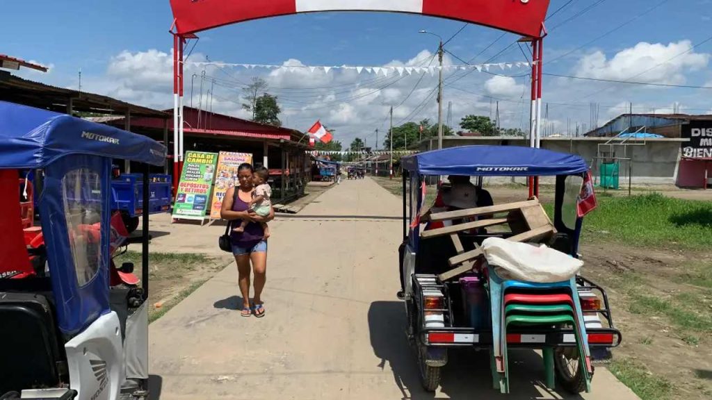 Entrada do povoado da Ilha de Santa Rosa, com mulher carregando criança e moto-táxi.