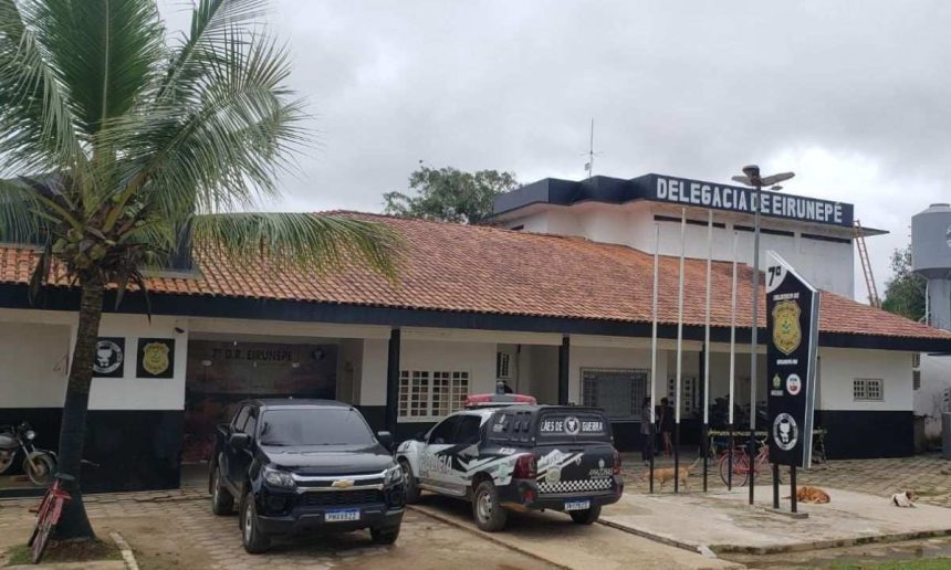 Fachada da delegacia de polícia de Eirunepé com viaturas e vegetação.