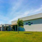 Fachada da Embrapa em dia ensolarado, com gramado e céu azul.