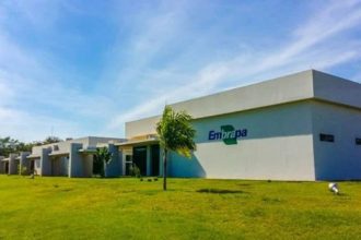 Fachada da Embrapa em dia ensolarado, com gramado e céu azul.