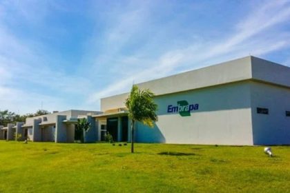 Fachada da Embrapa em dia ensolarado, com gramado e céu azul.