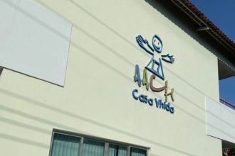 Fachada de prédio com logo 'AACV Casa Vida', em tons de azul, verde e marrom, e um desenho de uma pessoa.