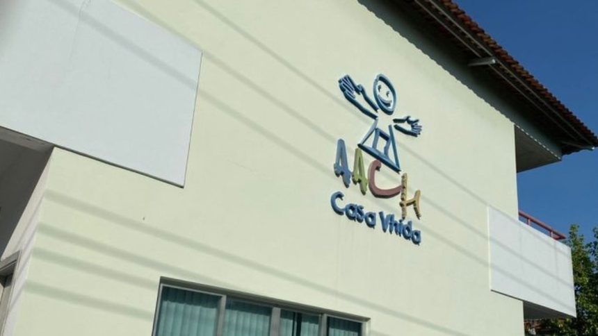 Fachada de prédio com logo 'AACV Casa Vida', em tons de azul, verde e marrom, e um desenho de uma pessoa.