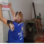 Fiscalização apreende alimentos irregulares em Manaus. Mulher coloca placa de interdição.