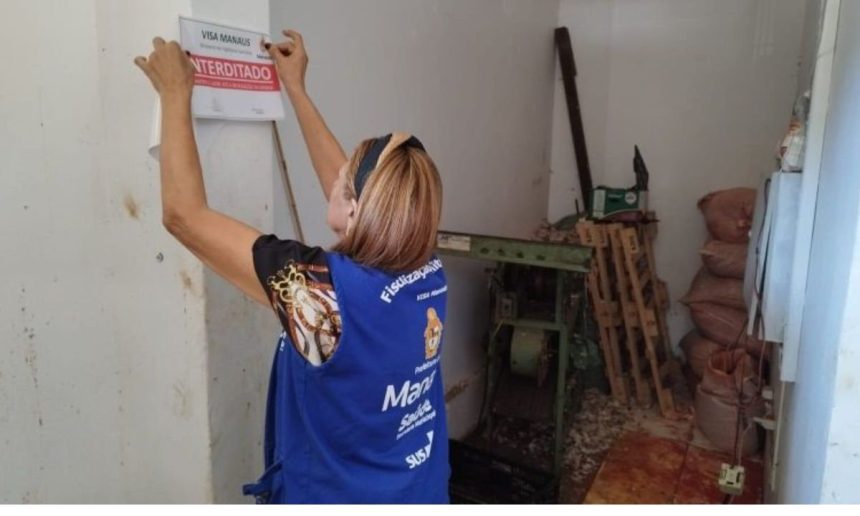 Fiscalização apreende alimentos irregulares em Manaus. Mulher coloca placa de interdição.