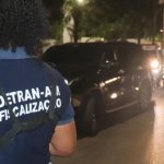 Fiscalização do Detran-AM em ação, com carro parado e agentes na rua.