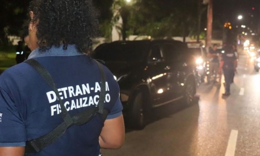 Fiscalização do Detran-AM em ação, com carro parado e agentes na rua.