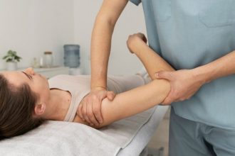 Fisioterapeuta realizando massagem no braço de paciente para aliviar dores.