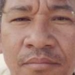 Foto de um homem com expressão séria, possivelmente um retrato.